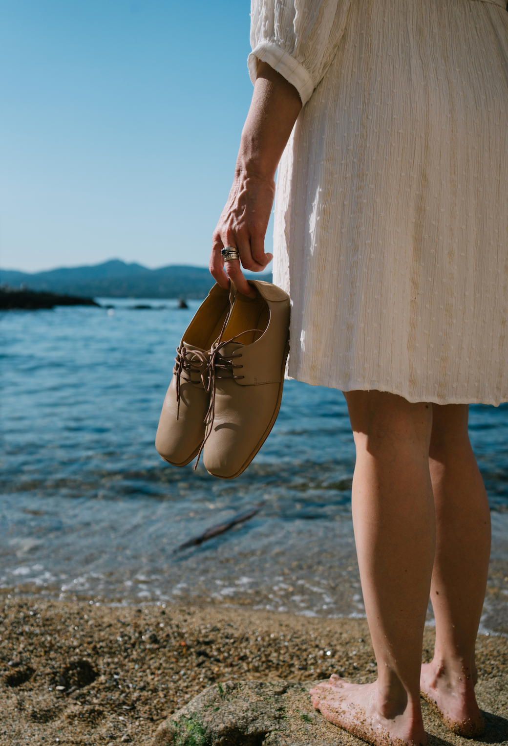 chaussures Le Plagiste femme tenues à la main devant la mer